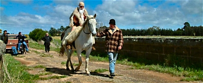 Film assistant leads Cohen (mounted on a horse) along a path whilst crew film from behind